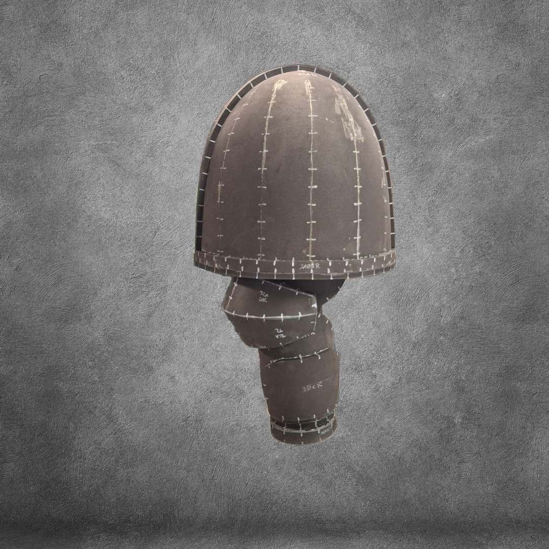 A sculptural object resembling a mushroom, crafted from stitched brown fabric pieces and inspired by an EVA foam template, stands against a textured gray background, showcasing the V.10 Tactical Arms Pattern.