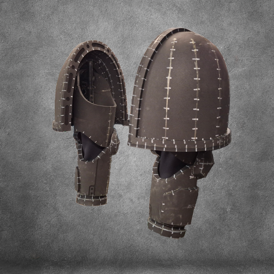 Two V.10 Tactical Arms Pattern helmets, brown with dome-shaped segmented design and metallic stitching details, are displayed against a textured gray background. Perfect for Galactic Warriors arms cosplay, these sci-fi helmets feature open fronts that reveal their intricate interior structure.