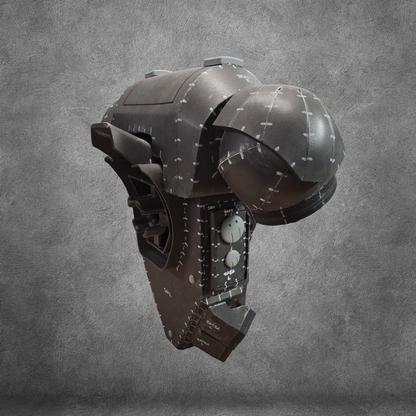 A dark, futuristic tactical backpack with segmented panels, bolts, and white markings—designed in the V.10 Tactical Backpack Pattern—is displayed against a textured gray background. The industrial, armored aesthetic echoes the high-tech enhancements seen in Galactic Warriors Tactical Remaster, making it a perfect source of inspiration for advanced EVA foam crafting enthusiasts.