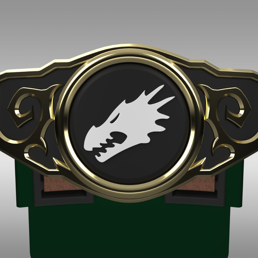 A close-up of a decorative belt buckle or emblem with a black oval center, gold-toned ornate border, and a white dragon head symbol. The piece is shown against a neutral gray gradient background with a dark green object partially visible below.