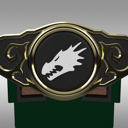 A close-up of a decorative belt buckle or emblem with a black oval center, gold-toned ornate border, and a white dragon head symbol. The piece is shown against a neutral gray gradient background with a dark green object partially visible below.