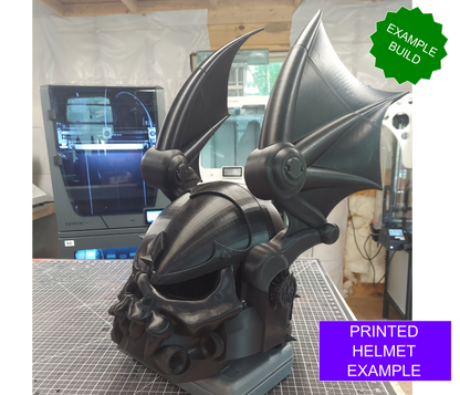 A detailed, black Midnight Rulers Helmet (3D Print | Files Only) with large bat wings sits on a table in front of a 3D printer. Green and purple labels read EXAMPLE BUILD and PRINTED HELMET EXAMPLE, highlighting the impressive quality possible using the included digital download files.