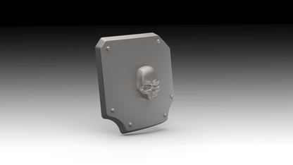 A gray 3D-printed shield-shaped plate with a raised skull emblem in the center and four small screw details around the border, shown on a black-to-white gradient background.