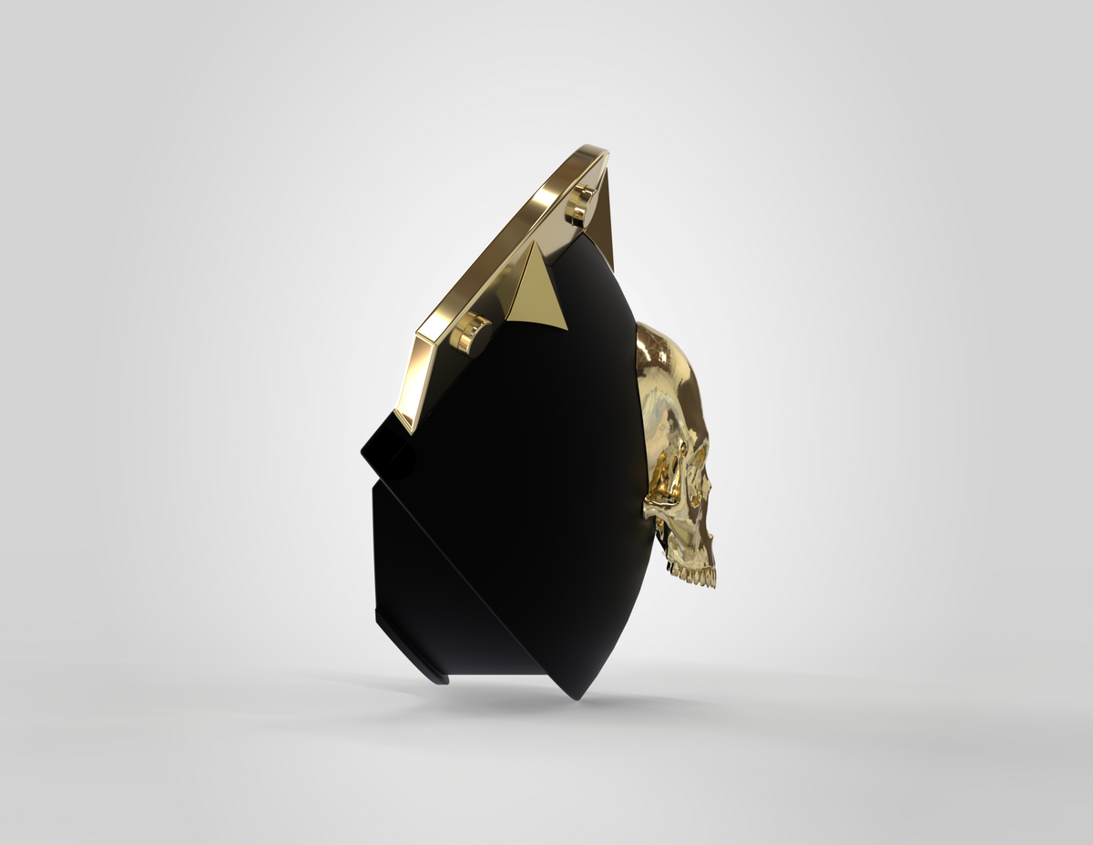 A gold skull, inspired by the V.10 Knee Skull Detail V.1 (3D Print | Files Only), is partially embedded in a glossy black and gold geometric shape, set against a plain light gray background.