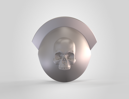 Showcased against a plain light background, the V.10 Knee Skull Detail V.1 (3D Print | Files Only) features a metallic, circular design with a prominent raised skull at its center and a smooth, curved top edge—perfect for enhancing your Galactic Warriors Version 10 cosplay. This striking detail is both functional and decorative, making it an excellent source of inspiration for creating your own custom 3D printable knee accessory.