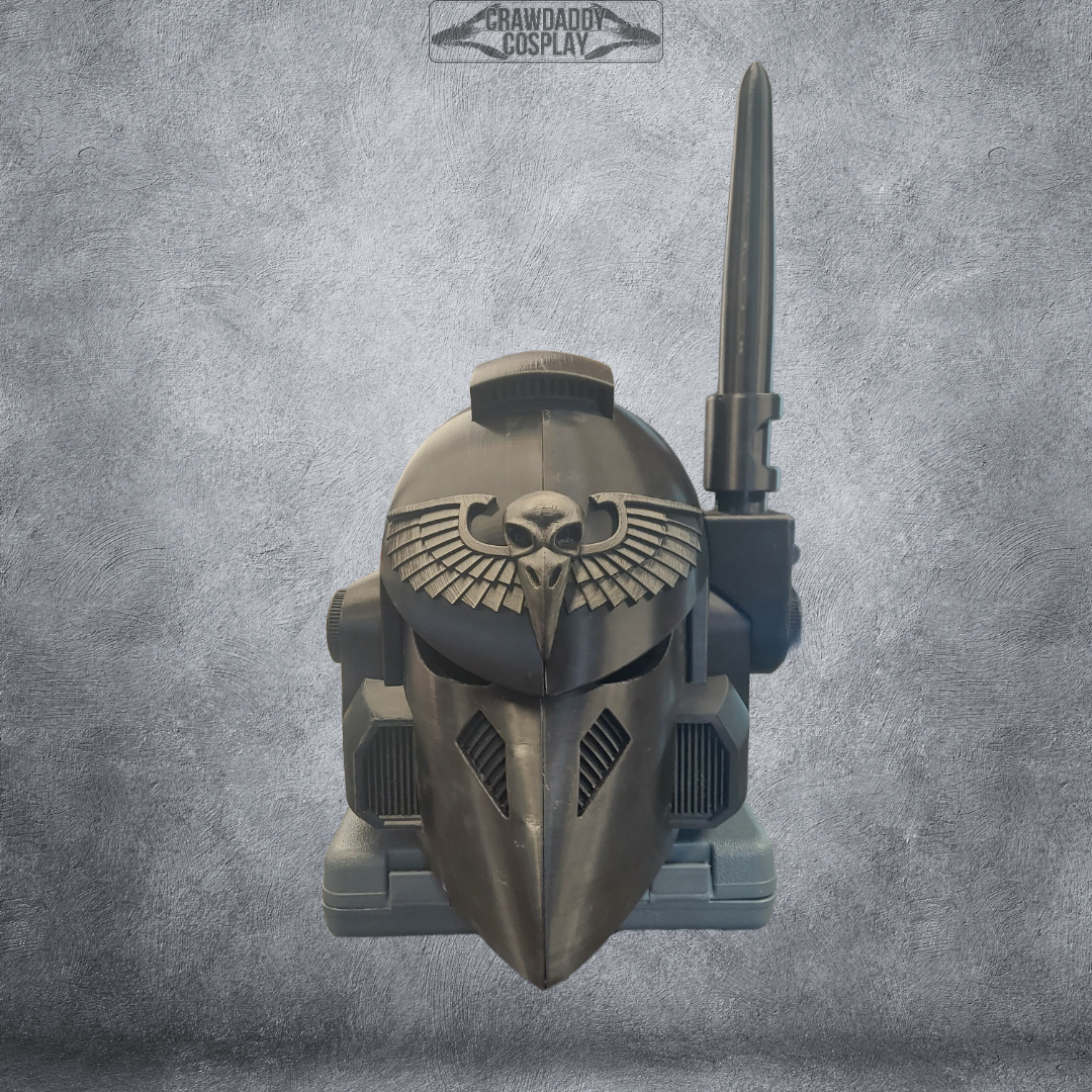 A black armored V.7 Eagle - Sable Sentry Helmet (3D Print | Files Only), featuring a winged skull emblem and a large radio antenna, is showcased against a textured gray background. Ideal for collectors or creators, this product offers high-quality 3D print files available as a convenient digital download.