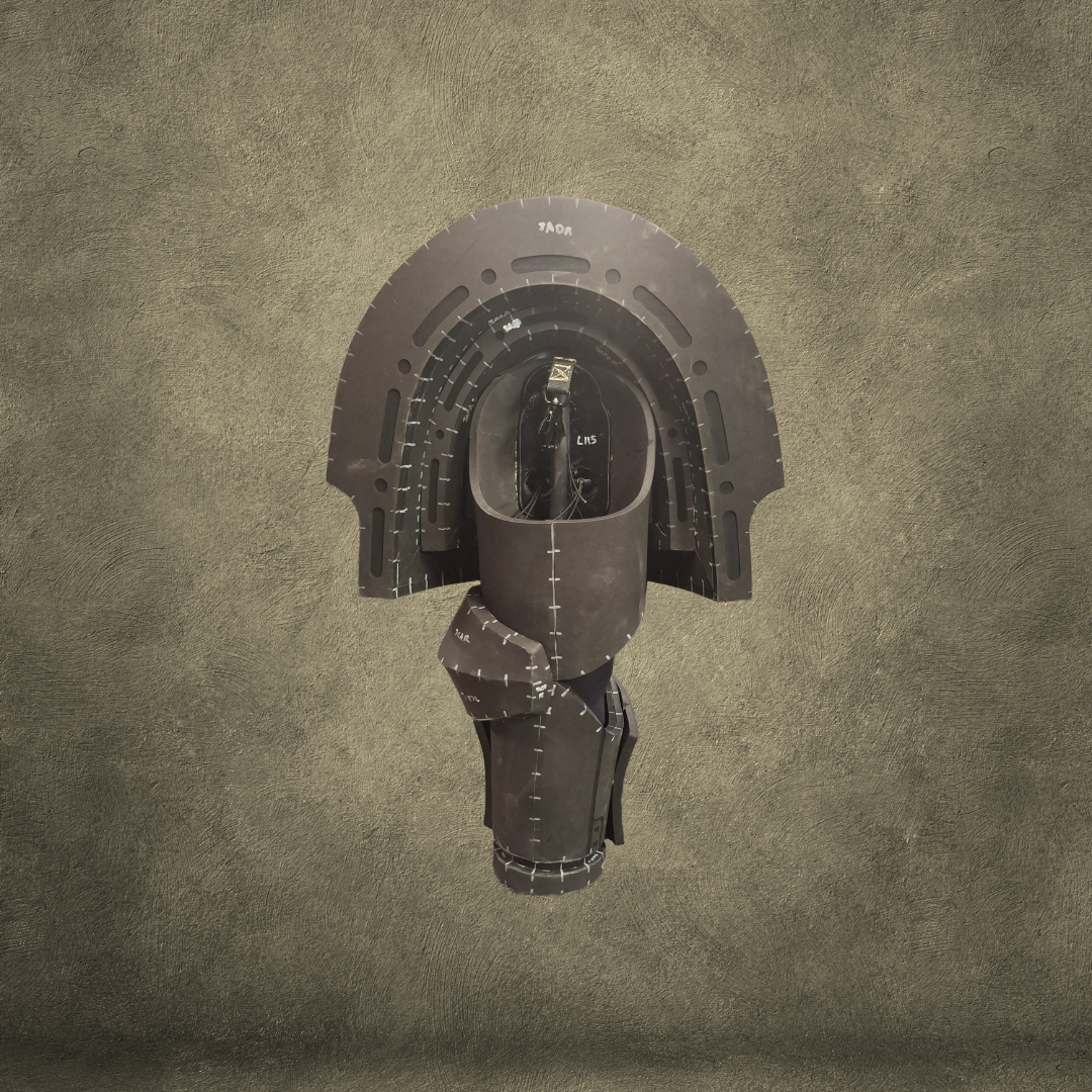 A black, segmented sculpture resembling a stylized helmet or mask is displayed against a textured brown background. Reminiscent of an EVA foam template for the V.10 Edge Warden Arms Pattern, the sculpture features curved layers with measurement markings, suggesting its potential use in crafting Tactical Edge Warden Arms.