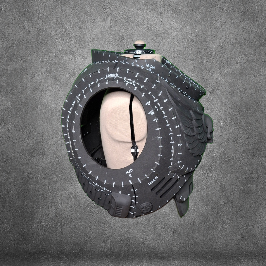 A mannequin head is placed inside a large, hollow black tire with white markings, set against a gray textured background, evoking the futuristic aesthetics of the V.10 Tactical Chest Pattern—perfect as inspiration for your next EVA foam template or digital download project.