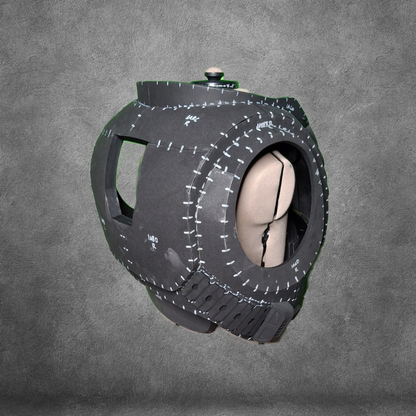 A spherical, black object with stitched seams and a beige interior sits against a gray textured background. Designed with large openings and reminiscent of Galactic Warriors’ armor, this structure is the V.10 Tactical Chest Pattern—a stylized, padded helmet or mask ideal for use as an EVA foam template or digital download for cosplay projects.