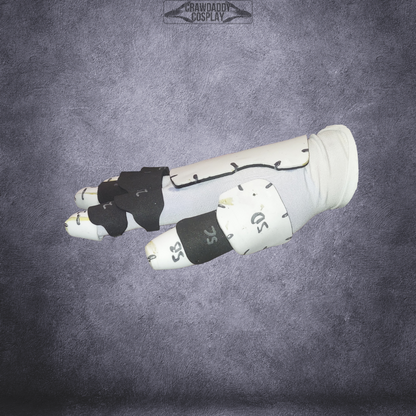 A white and black robotic glove or bracer with numbered sections, modeled for cosplay and displayed against a textured gray background. This design is based on the Galactic Warriors Universal Glove Pattern and is offered as a digital EVA foam template download for easy crafting.