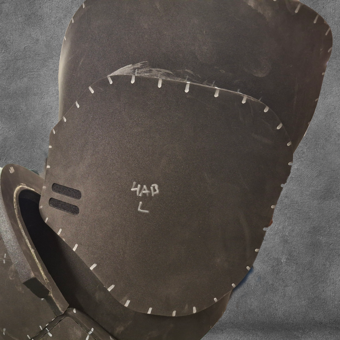 A close-up of a medieval-style helmet with visible stitching, a dark matte finish, and “HAP L” written in white on the faceplate is shown against a textured gray background. Perfect for cosplay enthusiasts, this look can be recreated with the V.10 Tactical Legs Pattern EVA foam template, available as a digital download.