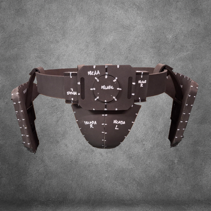 The V.10 Tactical Waist Pattern is a brown protective athletic cup and belt, inspired by the Galactic Warriors Waist, featuring handwritten white markings and measurement labels, displayed on a gray textured background.