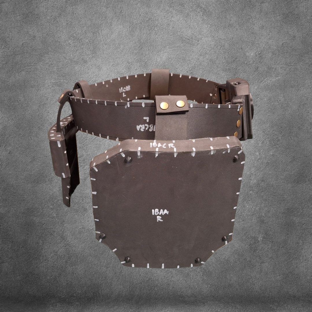 A brown V.10 Tactical Waist Pattern belt with a large, rectangular leather guard attached—styled in a Galactic Warriors fashion—is displayed against a gray textured background. White markings and visible stitching adorn the belt and guard. Ideal for cosplay or crafting, this EVA foam template is available as a digital download.