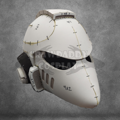 A white sci-fi or futuristic helmet, featuring visible seams, black eye slits, and text markings reminiscent of a Galactic Warriors Universal Beaked Helmet Pattern. The background is a gray textured surface with a CRAWDADDY COSPLAY watermark across the center.